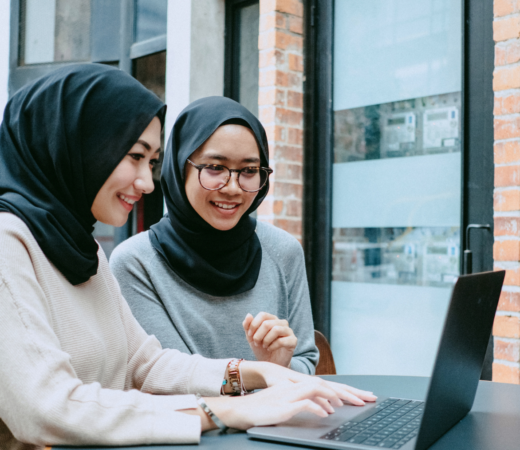 employees chatting with each other while one of them is typing on their laptop