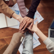 group of diverse employees all putting their hands together in the middle of the table