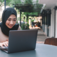 woman typing on her laptop while smiling