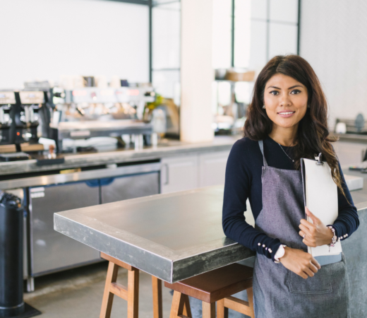 woman working at a cafe holding a clipboard