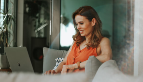 woman smiling while using her laptop at home