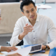 A group of professionals engaged in a discussion at a meeting table.