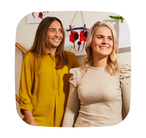 A photo of two women standing and smiling, appearing relaxed and engaged