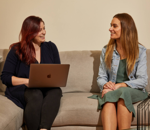 Two women sitting on a couch having a friendly conversation